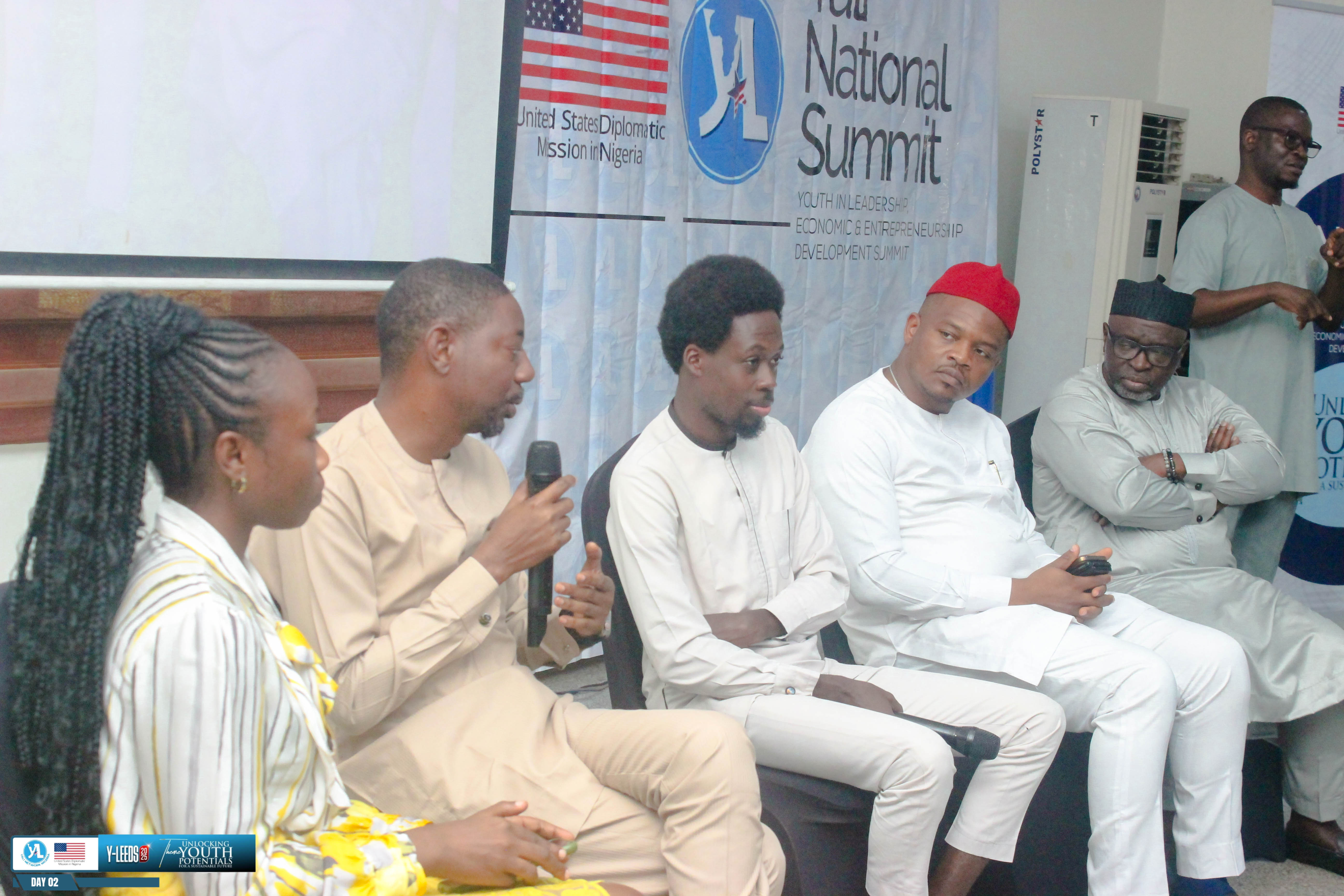 A five-person panel discussion on stage at Y-LEEDS 2025, with YALI Network Nigeria branding behind